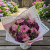 The centerpiece features soft pink gerbera daisies, radiating warmth and grace.